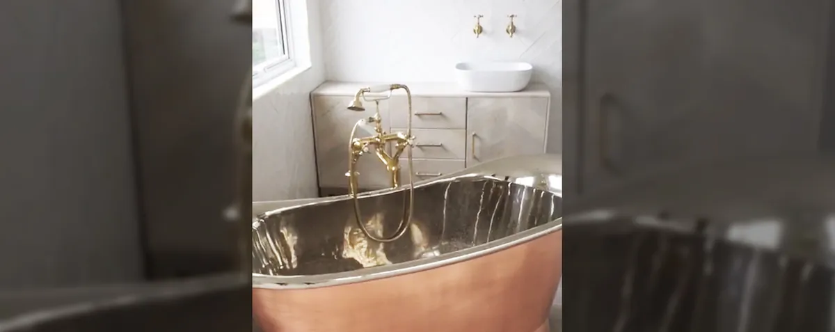 Copper roll-top bath with brass taps in a loft bathroom