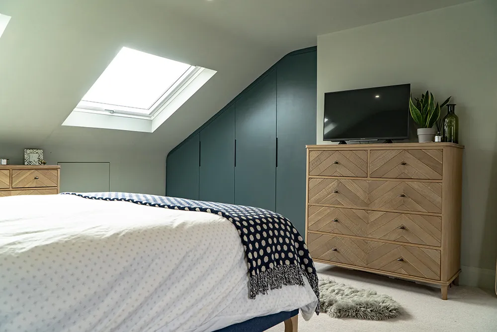 Loft bedroom with a rooflight and painted fitted wardrobes