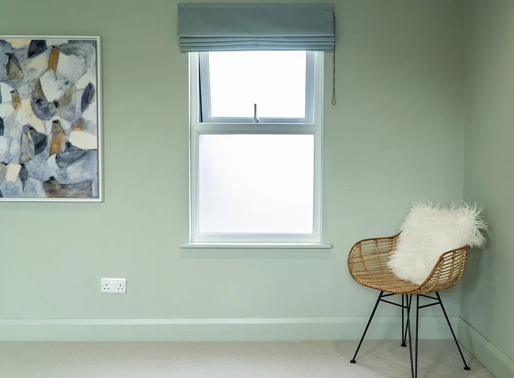 Loft bedroom with a sash window and soft green walls