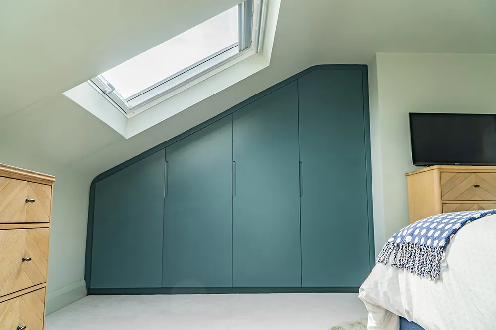Fitted wardrobes built under the eaves beneath a rooflight