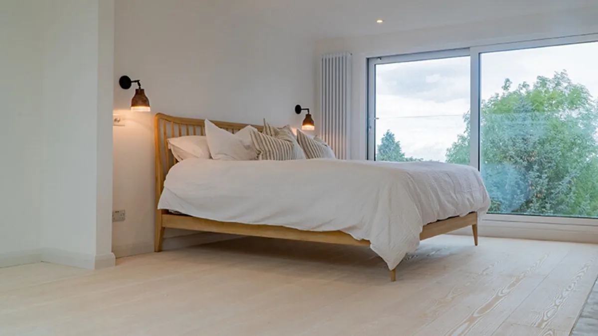 Finished loft bedroom with wide glazing looking out over trees