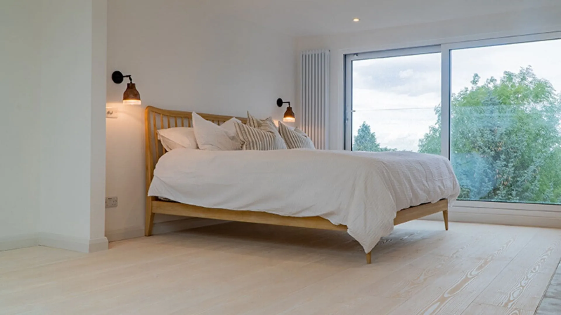 Finished loft bedroom with wide glazing looking out over trees