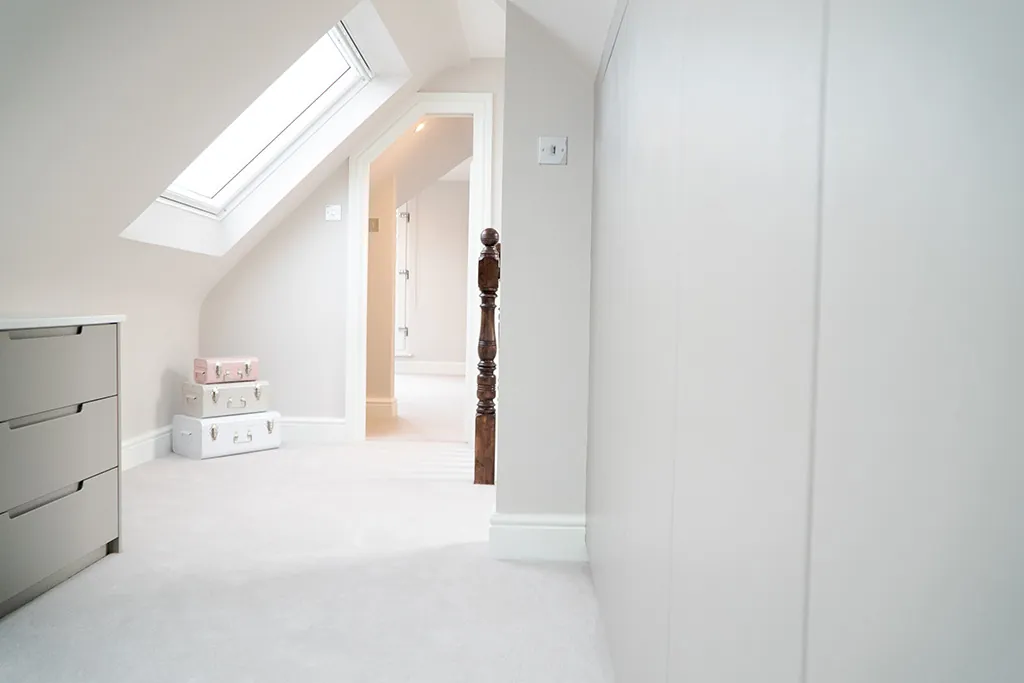 Loft bedroom with fitted drawers under the eaves and rooflights