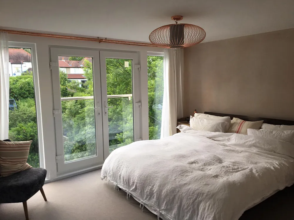 Loft bedroom with French doors opening onto a Juliet balcony