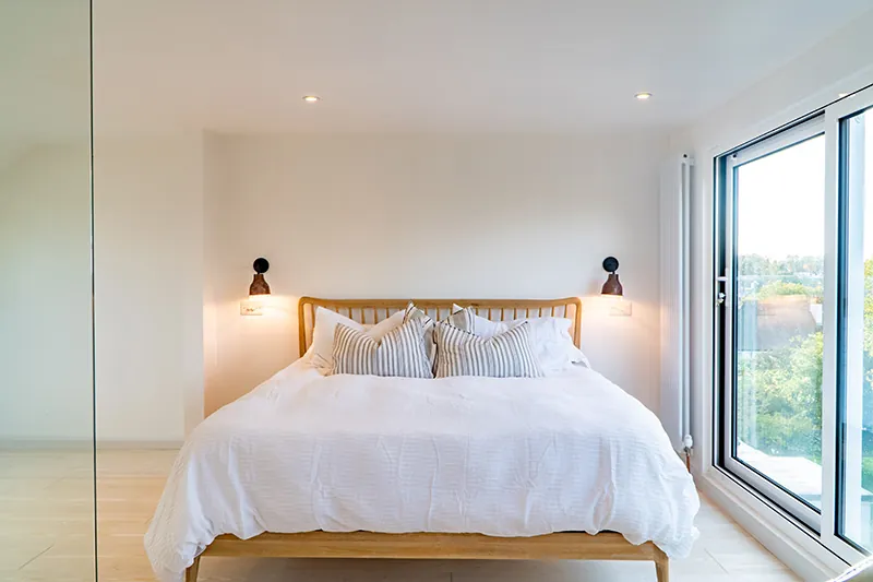 Loft bedroom with an oak bed beside full-height glazing