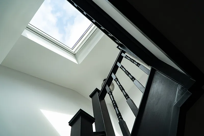Black painted staircase rising to a rooflight