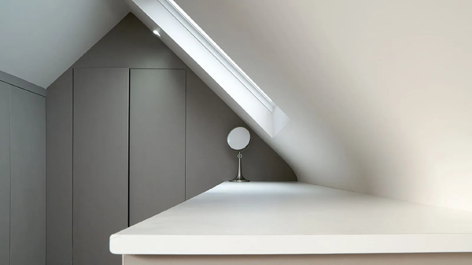 Fitted wardrobes and a dressing table built into the eaves of a loft room