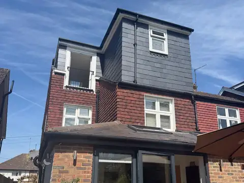 L-shaped dormer loft conversion clad in grey slate, seen from the back garden